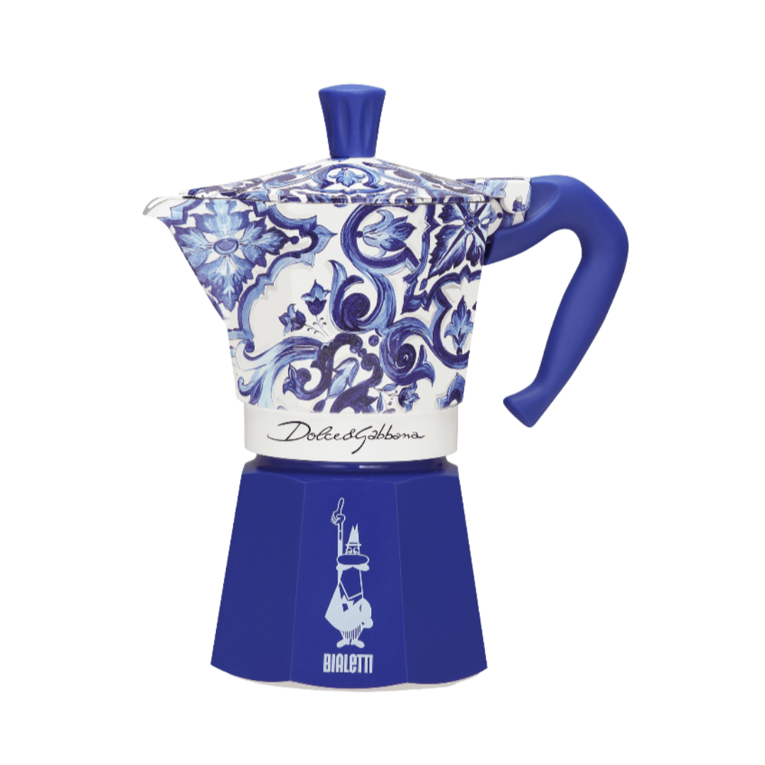 Bialetti coffee maker beside Dolce&Gabbana luxury accessories, epitomizing elegance and sophistication