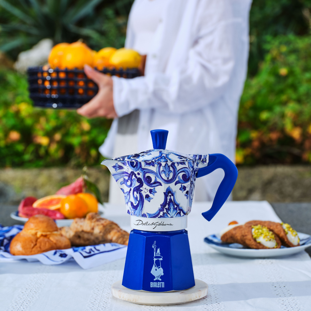 Bialetti coffee maker beside Dolce&Gabbana luxury accessories, epitomizing elegance and sophistication