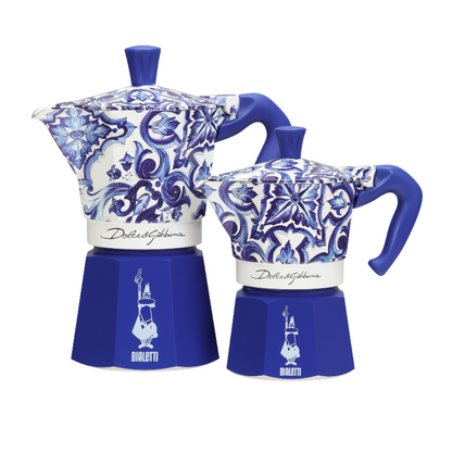 Bialetti coffee maker beside Dolce&Gabbana luxury accessories, epitomizing elegance and sophistication